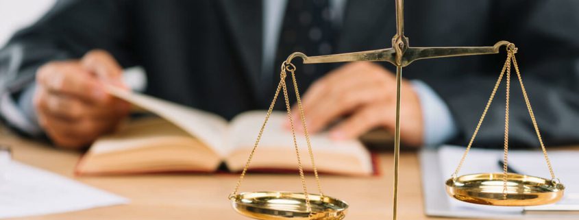 A lawyer reviewing documents with scales of justice on the desk.